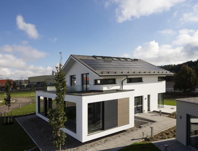 Maison moderne avec panneaux solaires sur le toit, grandes fenêtres et jardin.