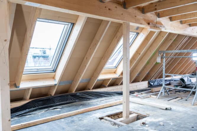 Grenier en cours de rénovation avec poutres apparentes et fenêtres de toit VELUX.