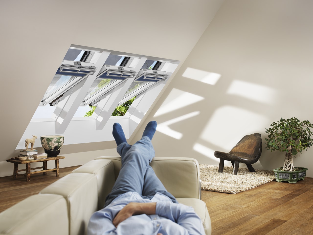 Homme allongé dans son canapé devant ses fenêtres de toit VELUX posées dans les combles.