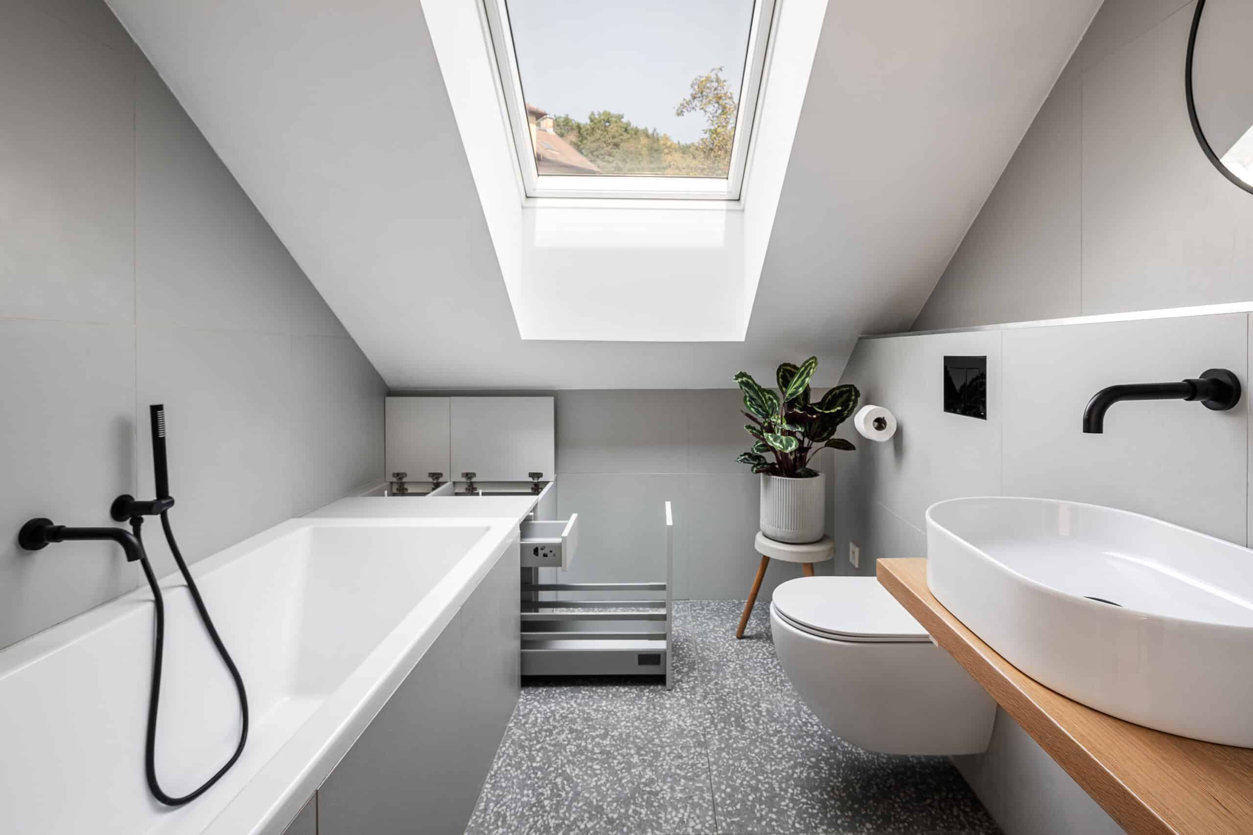 Salle de bains avec plafond mansard&eacute; et fen&ecirc;tre de toit VELUX, &eacute;quipements modernes.