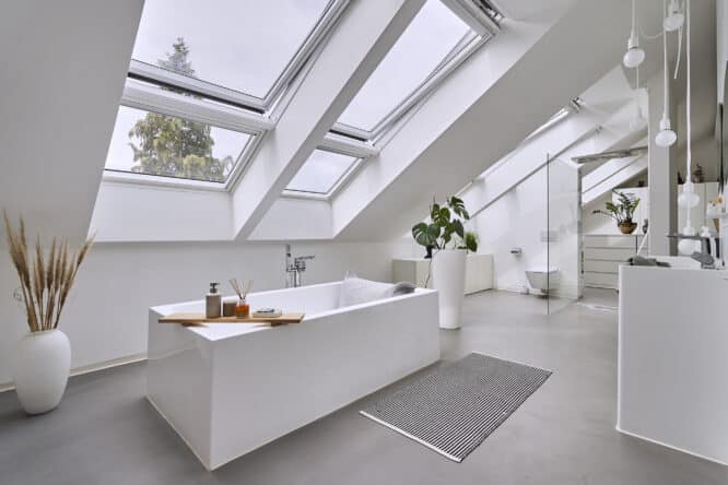 Salle de bains mansardée avec plafond en pente et fenêtres de toit VELUX, design moderne.