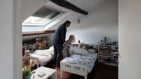 Père couchant ses deux enfants dans une chambre sous combles