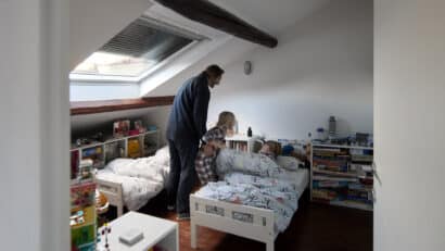 Père couchant ses deux enfants dans une chambre sous combles