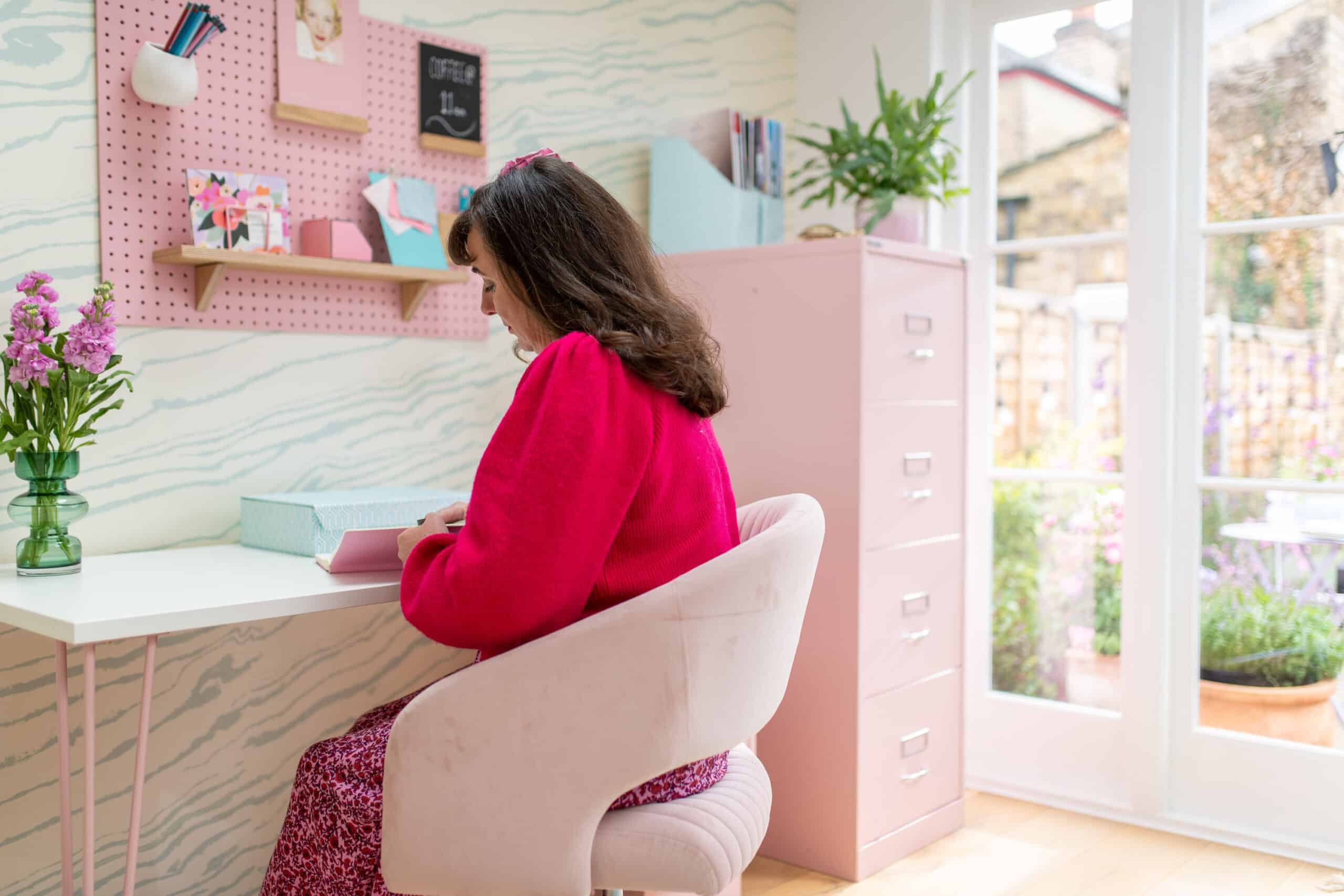 Bureau sous pente &agrave; domicile avec une d&eacute;coration rose, un bureau, une chaise et une grande fen&ecirc;tre.