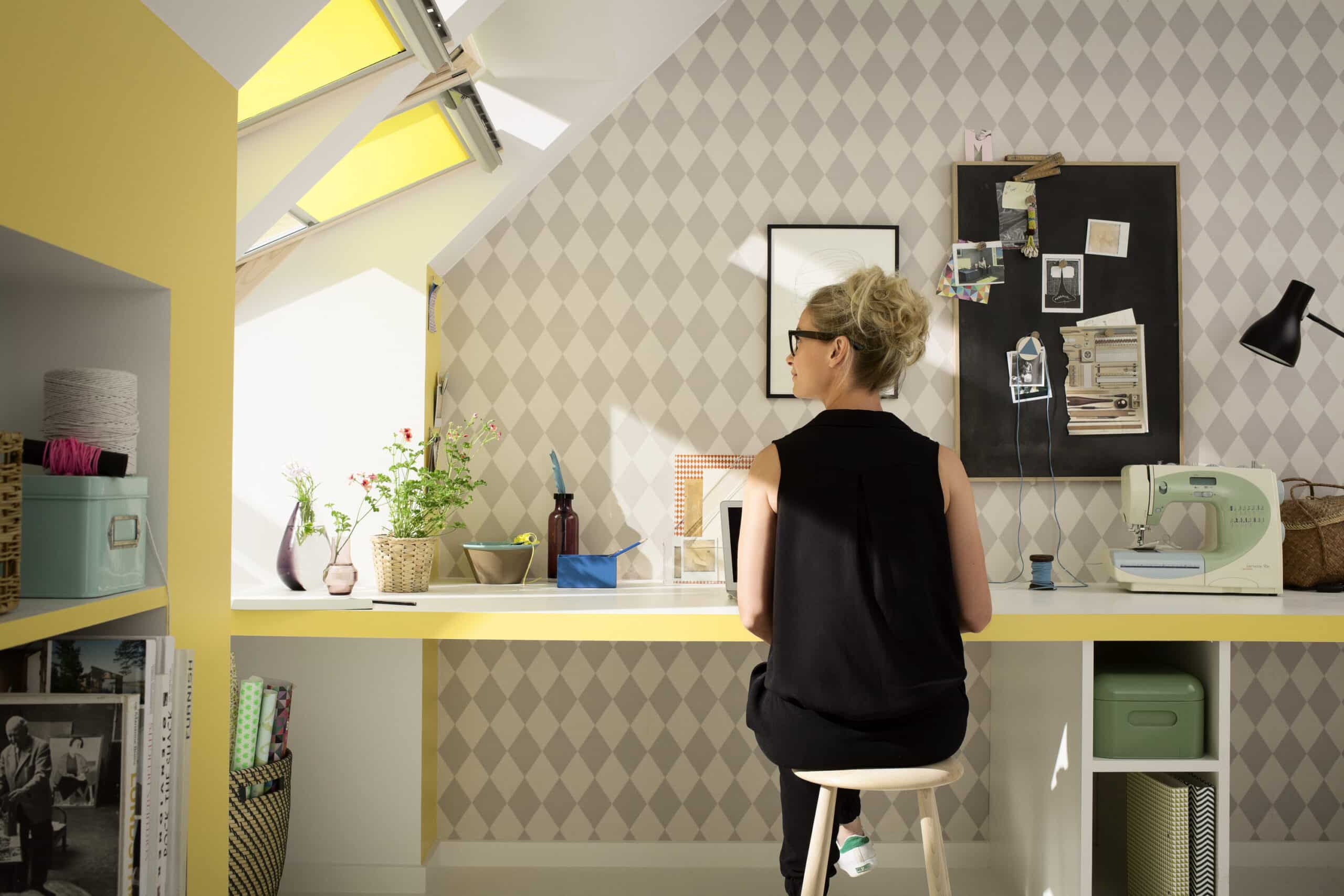 Espace de travail sous les combles avec fen&ecirc;tres de toit VELUX, machine &agrave; coudre et mat&eacute;riel de loisirs cr&eacute;atifs.