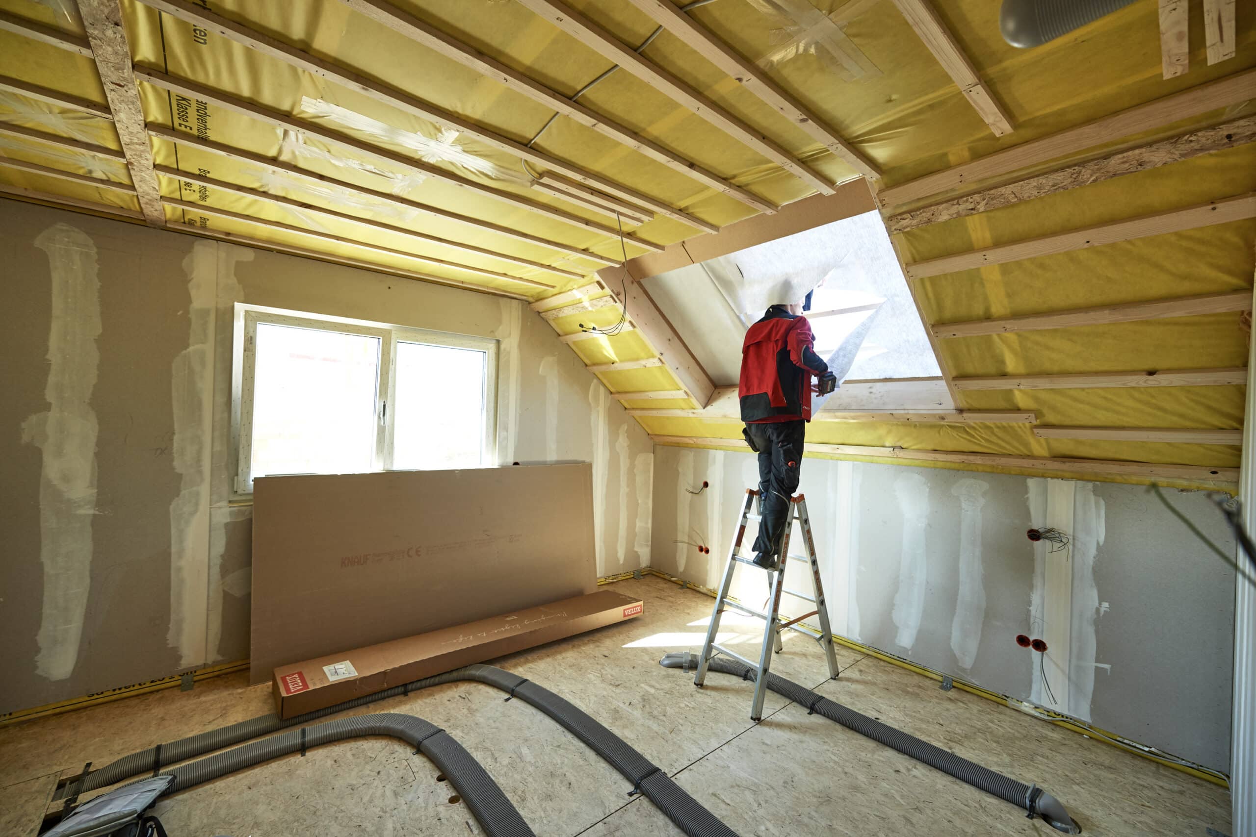 Ouvrier installant une fen&ecirc;tre de toit VELUX dans une pi&egrave;ce sous combles avec un plafond en pente.
