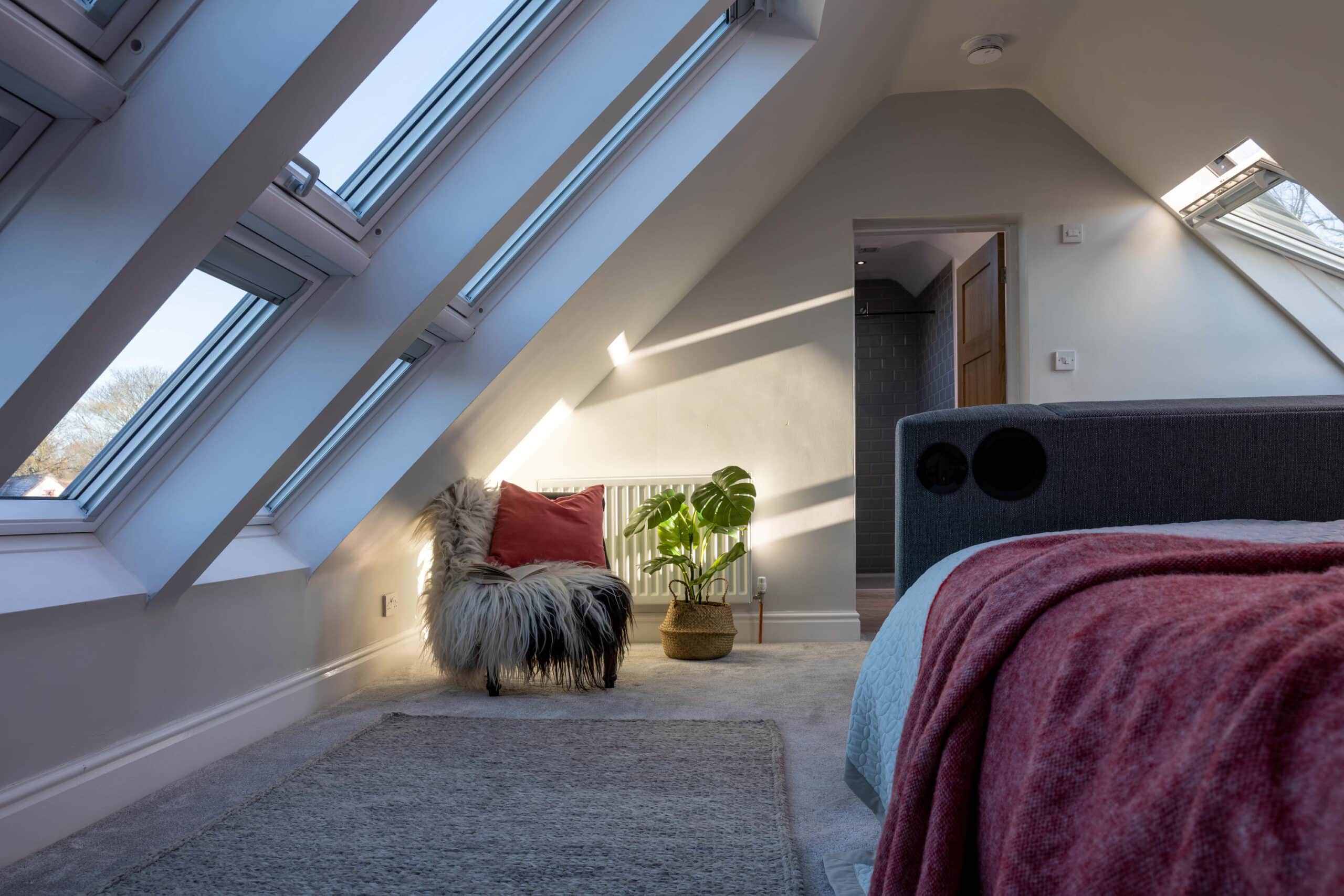 Chambre sous combles avec plafond en pente et fen&ecirc;tres de toit VELUX, d&eacute;coration chaleureuse.