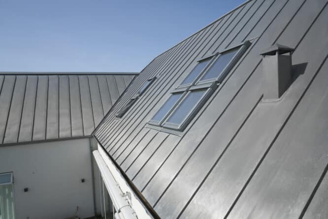 Toit métallique à forte pente avec fenêtres de toit VELUX et cheminée.