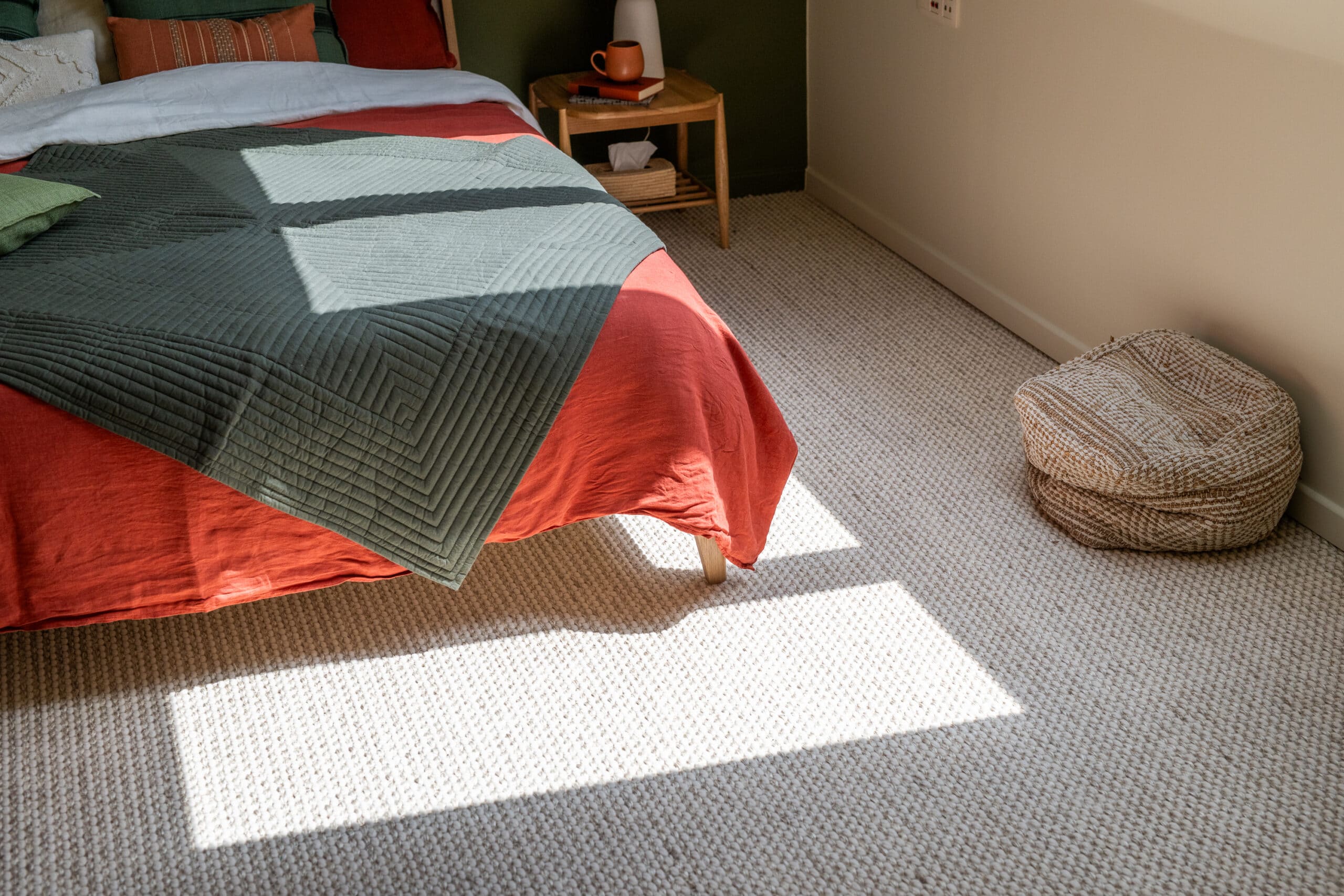Chambre sous pente avec de la lumi&egrave;re du soleil sur la moquette, une literie color&eacute;e et une table de chevet.