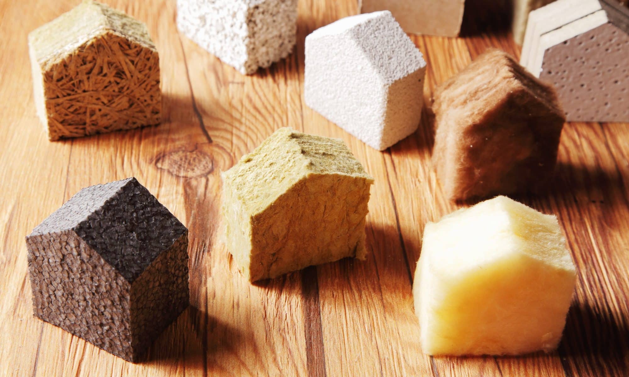Plusieurs isolants naturels découpés en forme de maison et déposés sur une table.