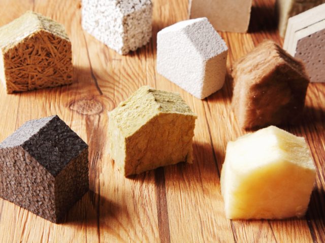 Plusieurs isolants naturels découpés en forme de maison et déposés sur une table.