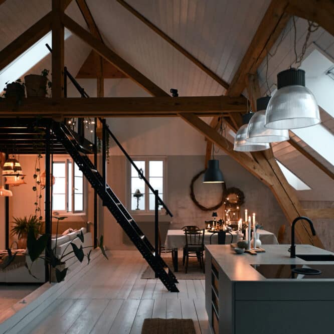 Salle à manger et cuisine mansardées avec fenêtres de toit VELUX et poutres apparentes.