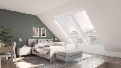 Chambre mansardée avec plafond en pente et grandes fenêtres de toit VELUX.