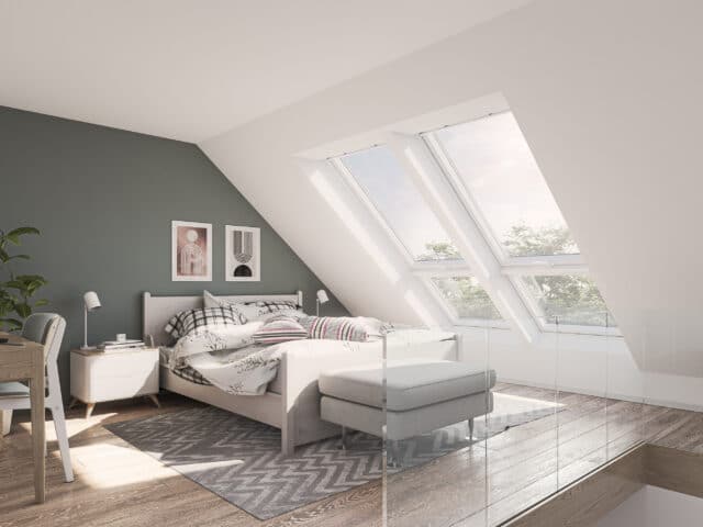 Chambre mansardée avec plafond en pente et grandes fenêtres de toit VELUX.