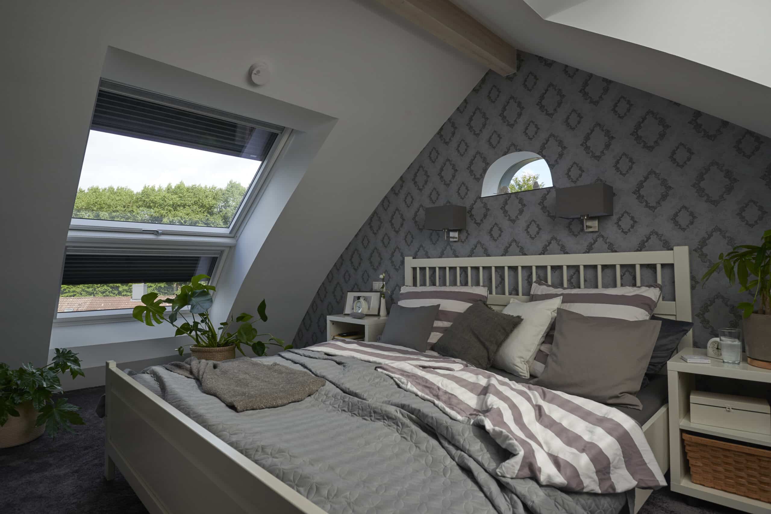 Chambre mansard&eacute;e avec plafond en pente et fen&ecirc;tre de toit VELUX, d&eacute;coration chaleureuse.