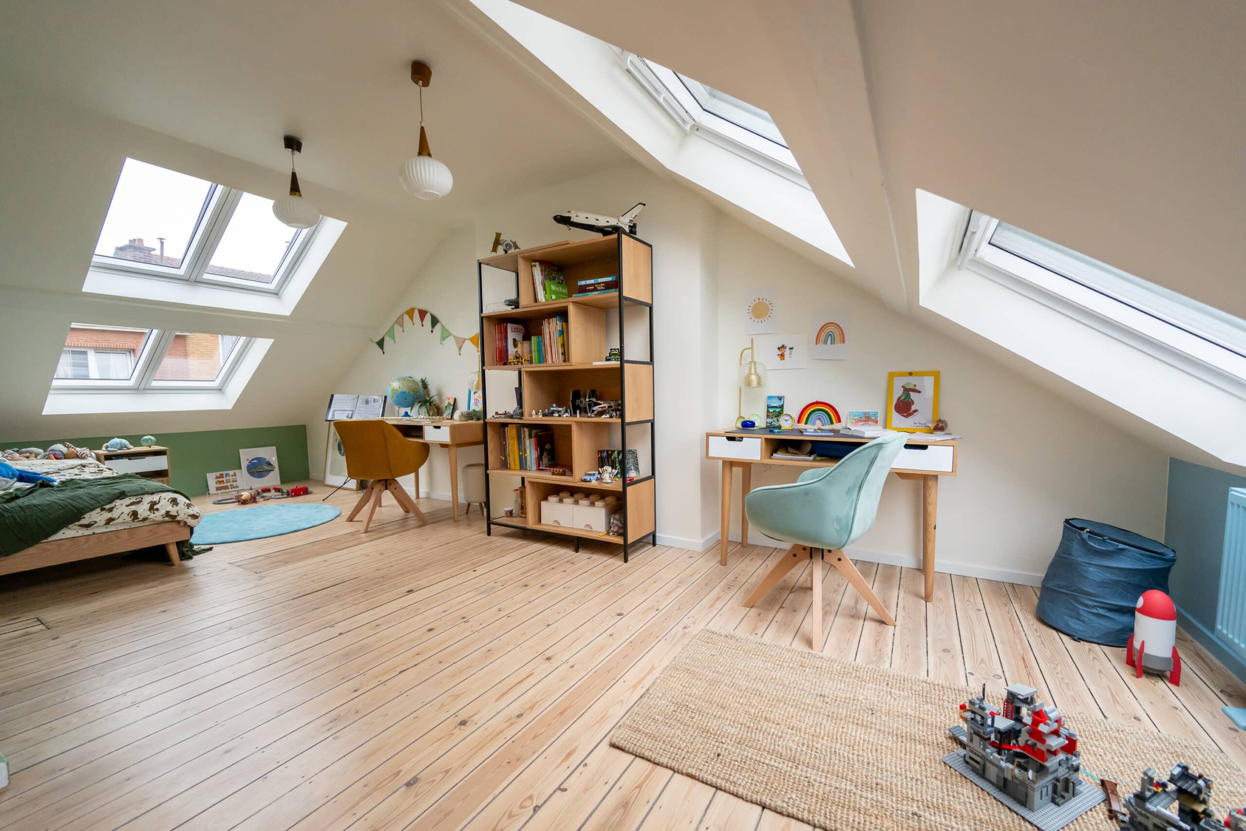 Chambre d'enfant mansard&eacute;e avec plafond en pente et fen&ecirc;tres de toit VELUX, d&eacute;coration color&eacute;e.