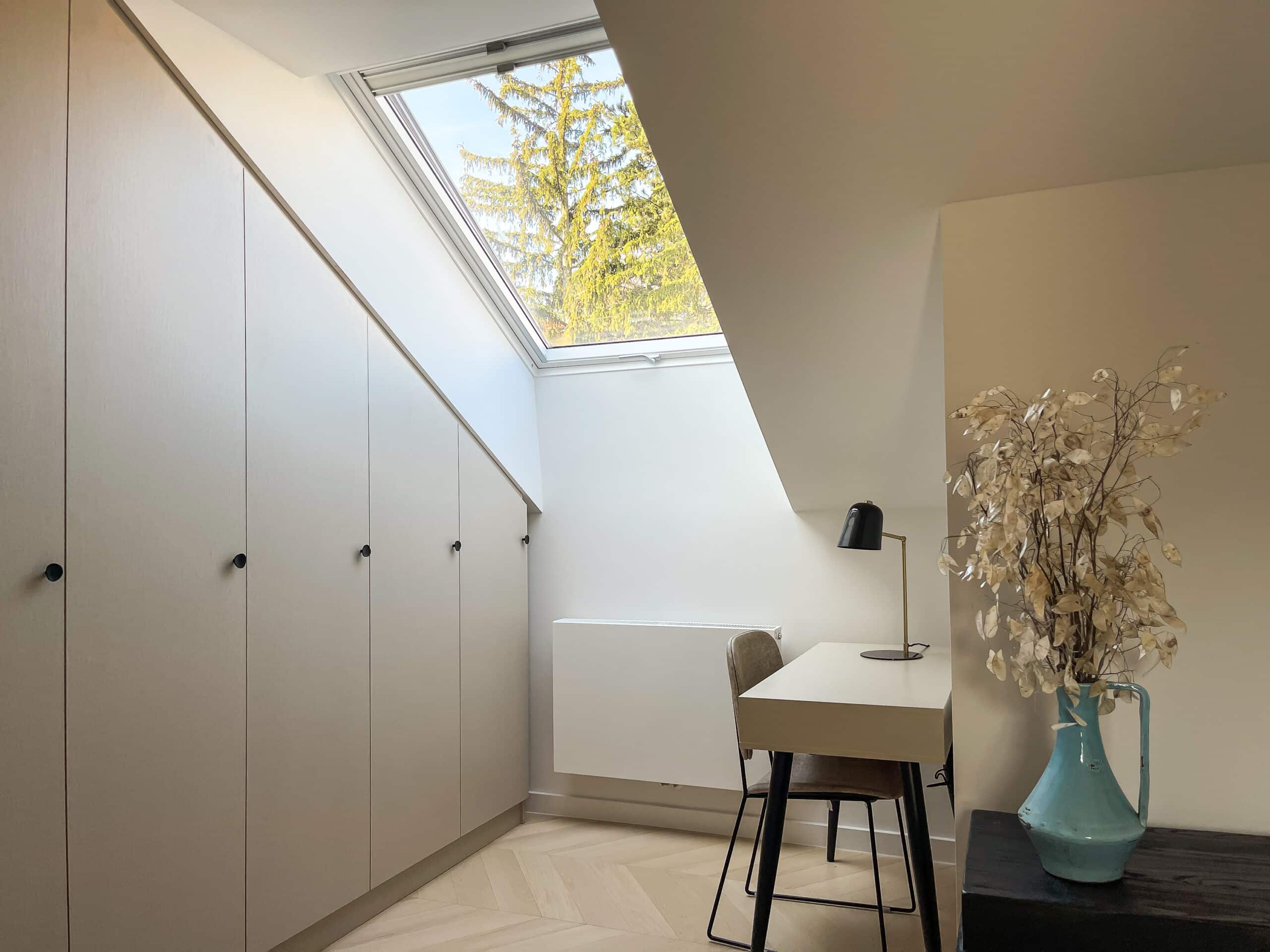 Espace de travail sous les combles avec plafond mansard&eacute; et fen&ecirc;tre de toit VELUX, bureau et rangements.