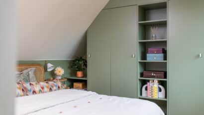 Chambre mansardée avec plafond en pente, décoration verte et armoire intégrée.