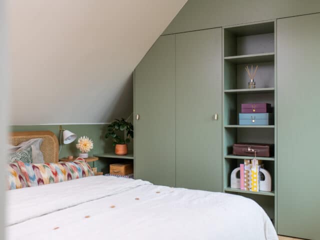 Chambre mansardée avec plafond en pente, décoration verte et armoire intégrée.