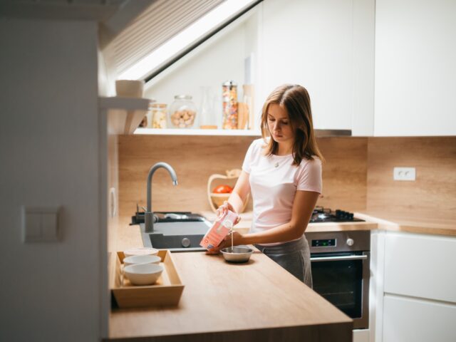 Jeune fille se versant à boire dans une cuisine sous combles.