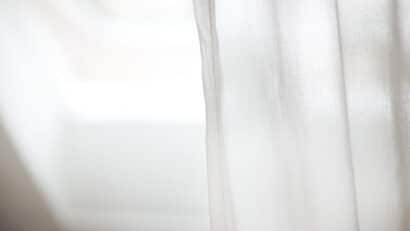 Gros plan sur un rideau blanc éclairé par la lumière d'une fenêtre de toit VELUX.