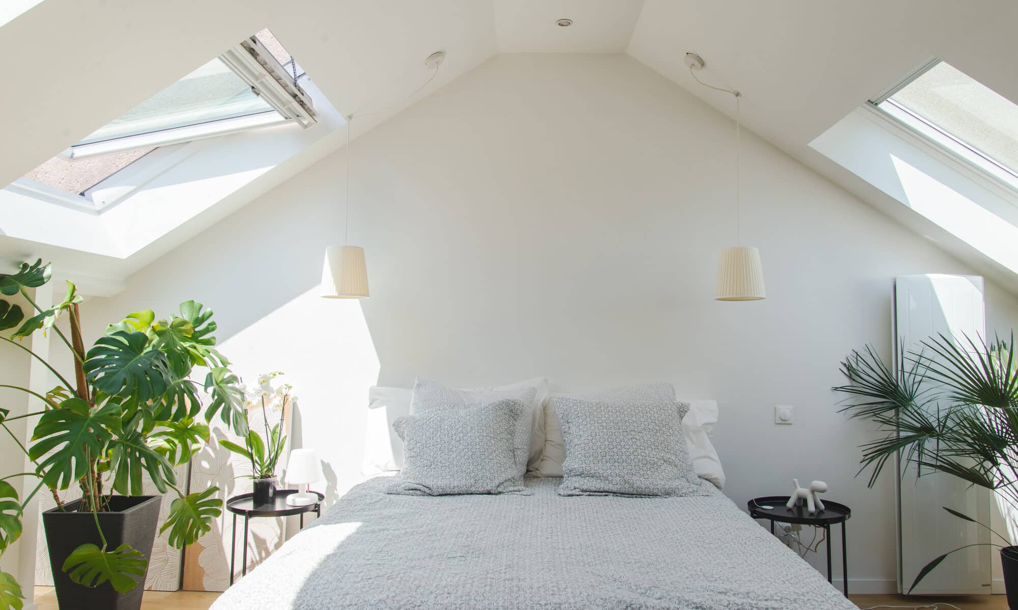 Chambre mansardée avec plafond incliné et fenêtres de toit VELUX, lumineuse et aérée.