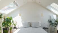 Chambre mansardée avec plafond incliné et fenêtres de toit VELUX, lumineuse et aérée.