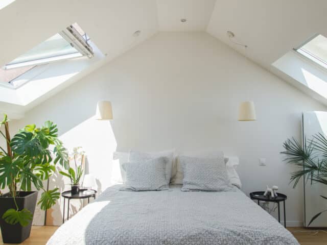 Chambre mansardée avec plafond incliné et fenêtres de toit VELUX, lumineuse et aérée.
