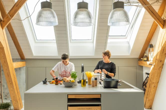 Cuisine moderne avec fenêtres de toit VELUX et poutres apparentes.