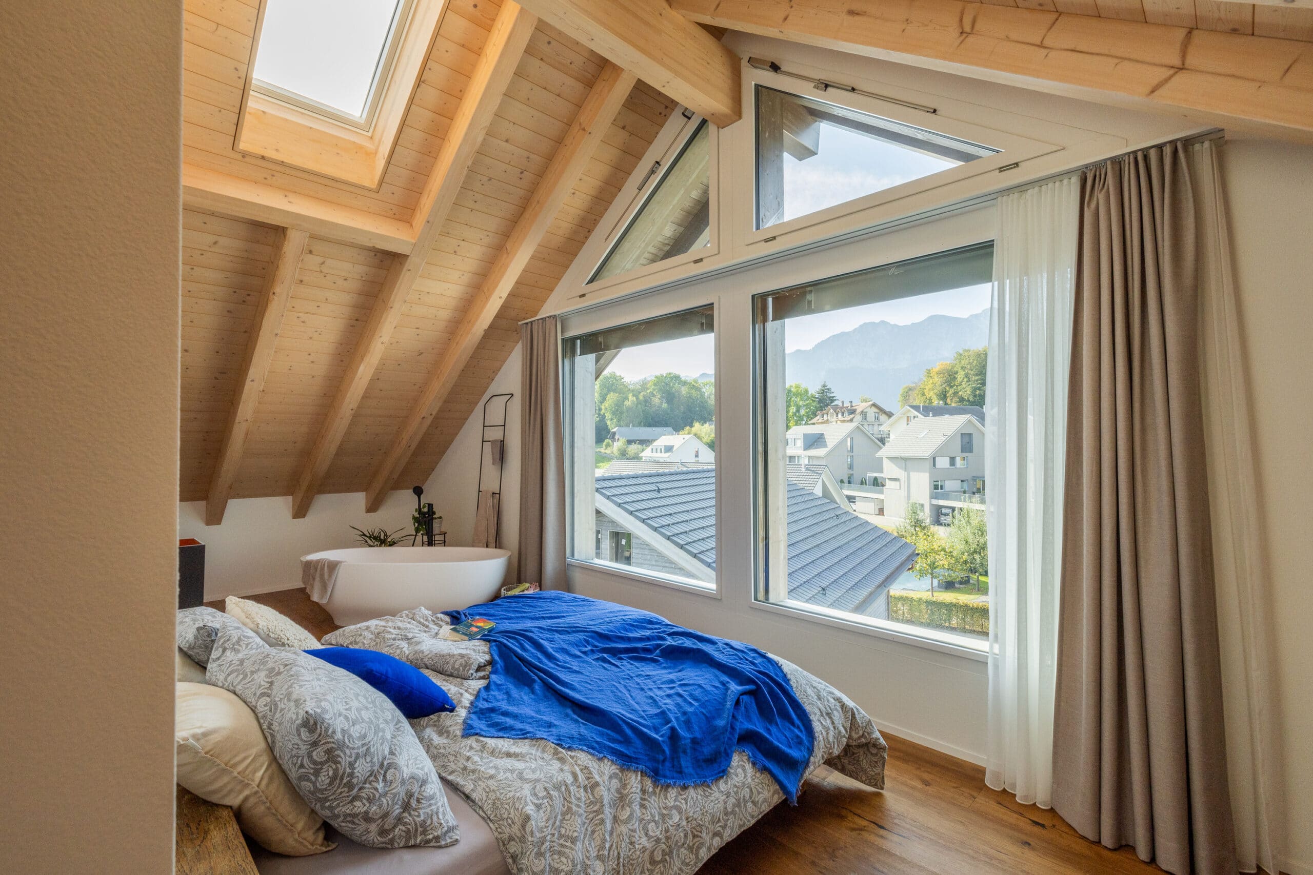 Chambre sous les combles avec plafond en pente, fen&ecirc;tre de toit VELUX et vue panoramique.