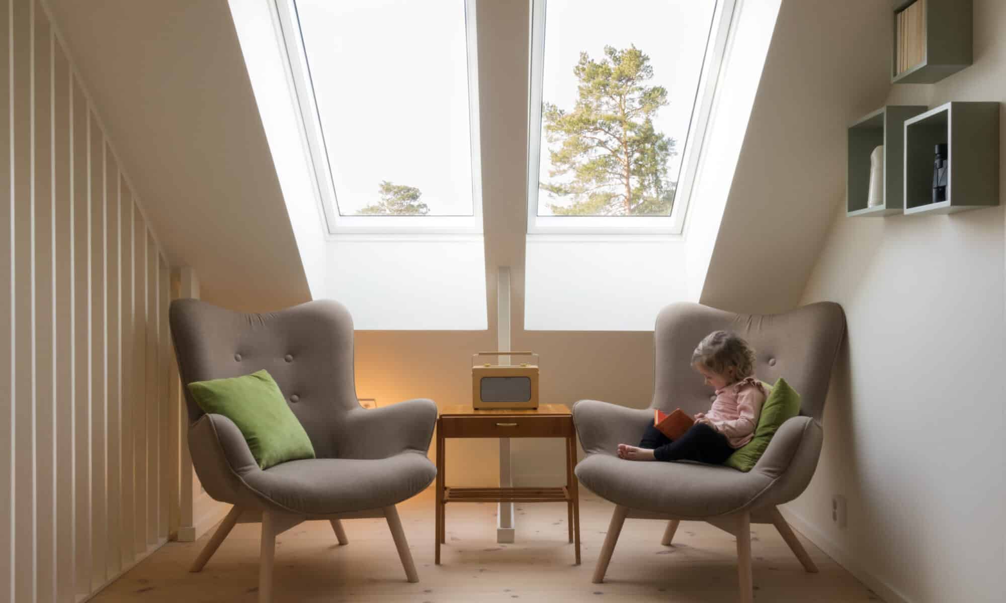 Enfant lisant sur un fauteuil près d'une fenêtre de toit VELUX.