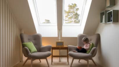 Enfant lisant sur un fauteuil près d'une fenêtre de toit VELUX.