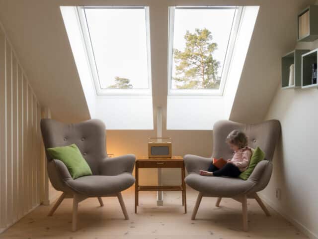 Enfant lisant sur un fauteuil près d'une fenêtre de toit VELUX.
