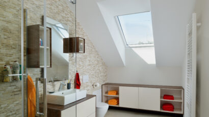 Salle de bains avec plafond mansardé et fenêtre de toit VELUX, équipements modernes.