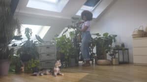 Jeune femme prenant soin de ses plantes dans un appartement sous combles.