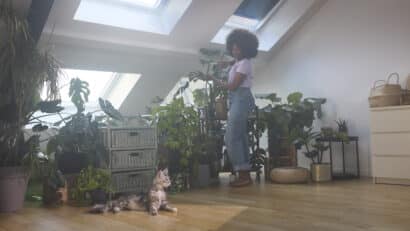 Jeune femme prenant soin de ses plantes dans un appartement sous combles.