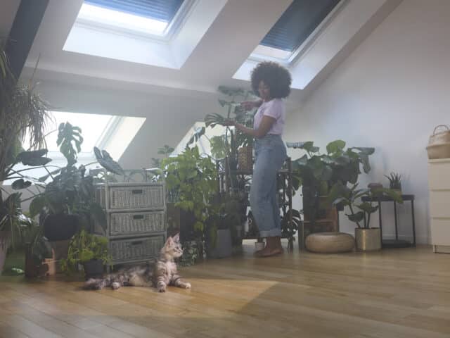 Jeune femme prenant soin de ses plantes dans un appartement sous combles.
