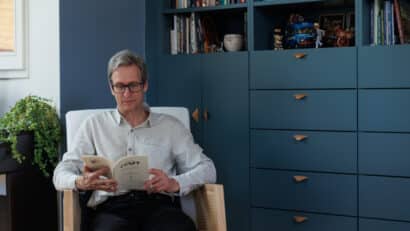 Homme lisant un livre devant une bibliothèque sur mesure dans un appartement sous combles.