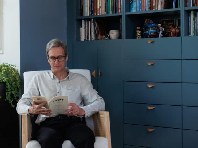Homme lisant un livre devant une bibliothèque sur mesure dans un appartement sous combles.