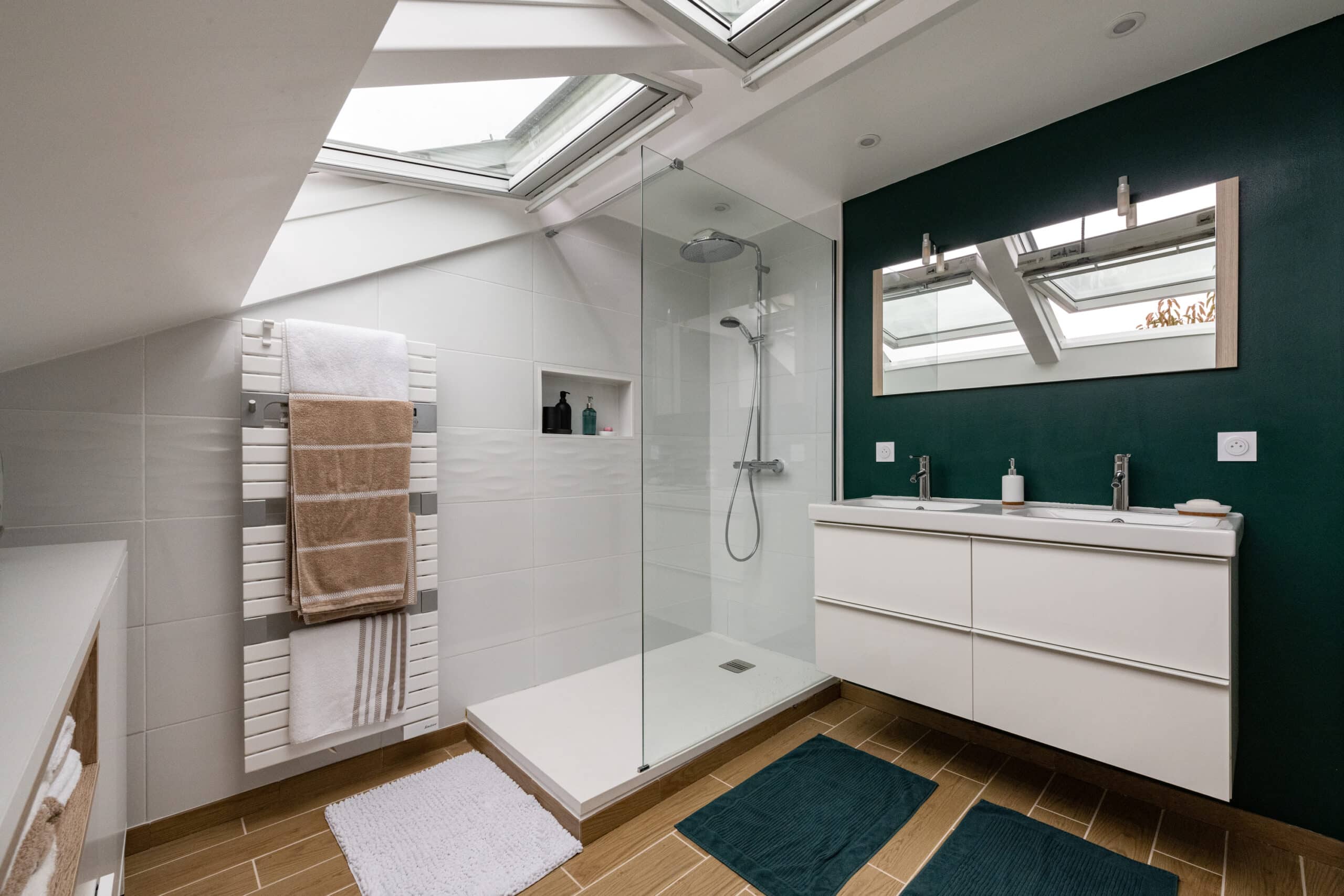 Salle de bains sous combles avec plafond en pente et fenêtres de toit VELUX, au design moderne.