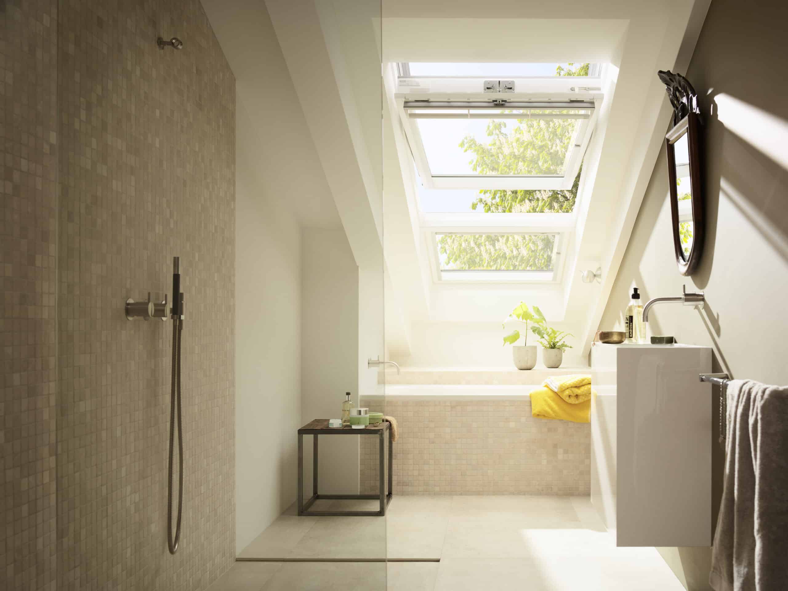 Salle de bains sous combles avec plafond en pente et fenêtre de toit VELUX ouverte, lumière naturelle.