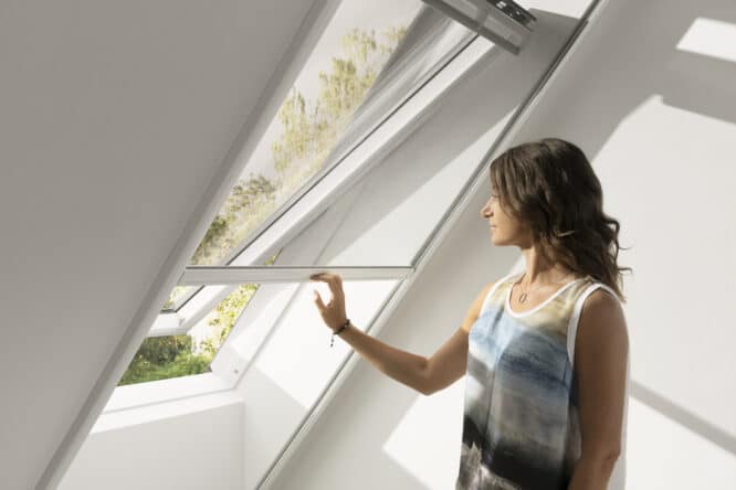 Chambre mansardée avec fenêtre de toit VELUX ouverte, laissant entrer la lumière naturelle.