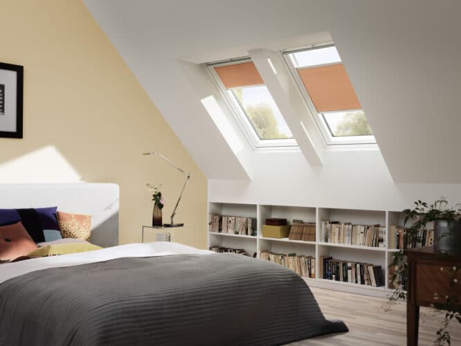 Chambre mansardée avec plafond en pente et fenêtres de toit VELUX, décoration chaleureuse.
