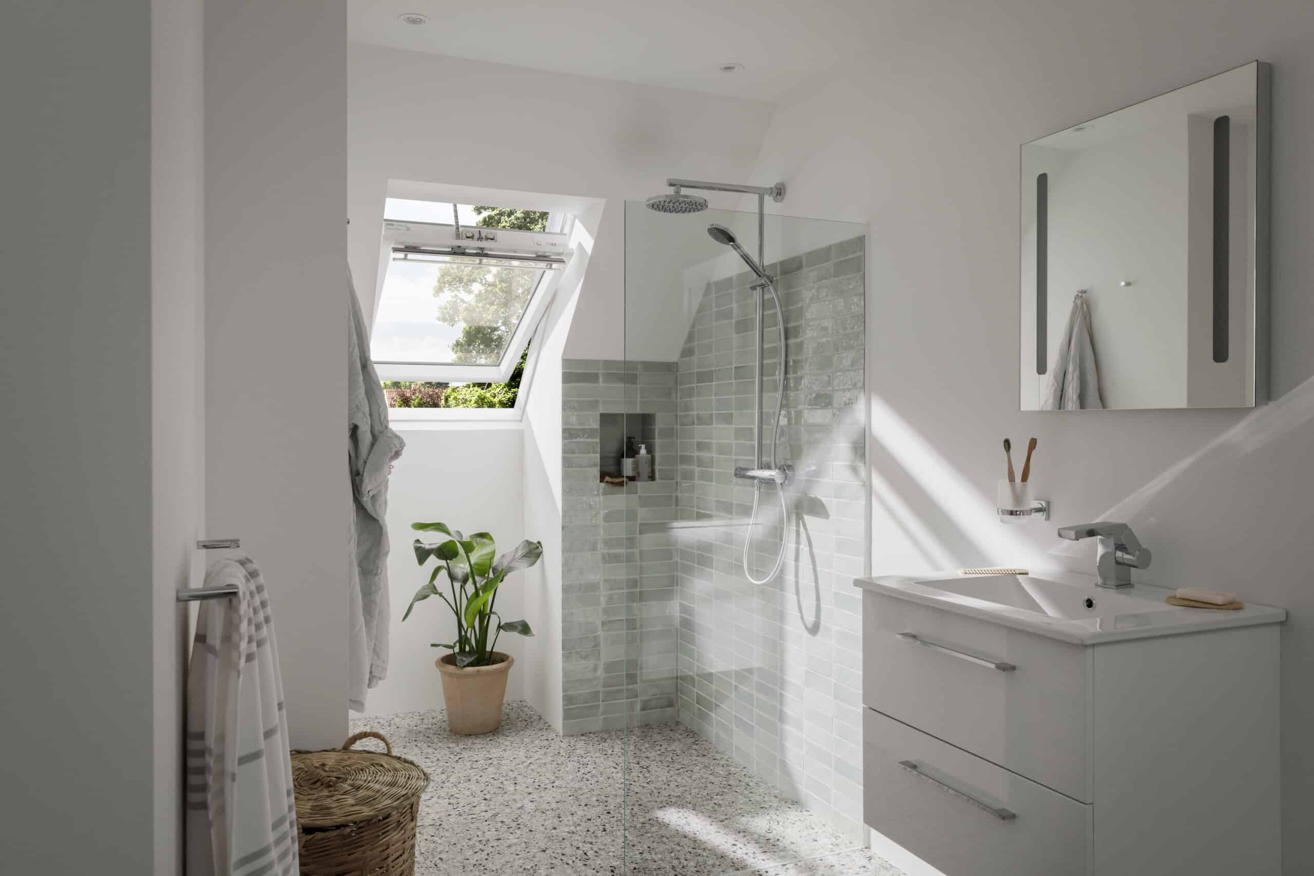 Douche sous pente avec fenêtre de toit VELUX, douche moderne et meuble-lavabo.