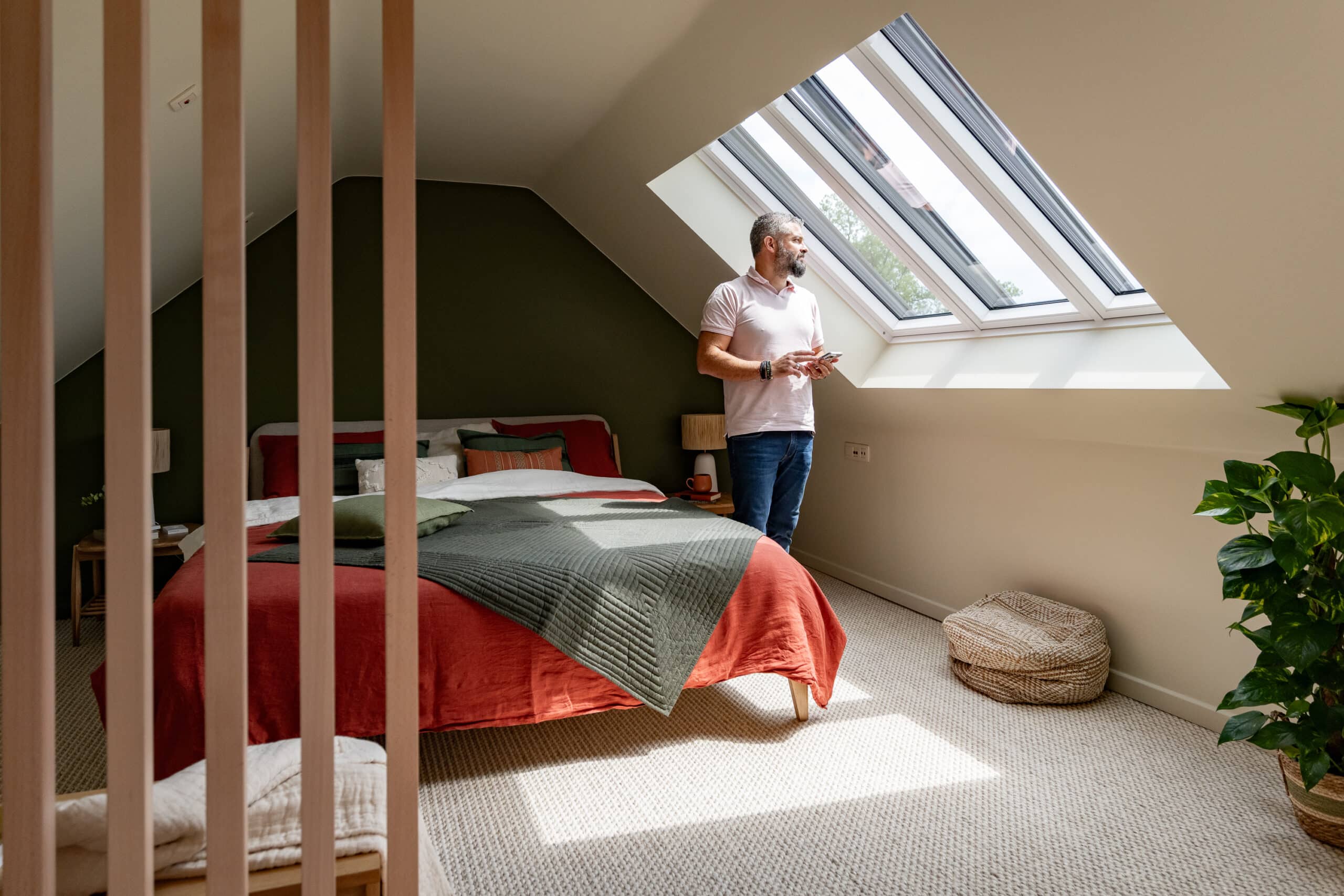 Chambre sous les combles avec plafond en pente et grande fen&ecirc;tre de toit.