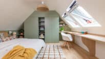 Chambre sous comble avec de grandes fenêtres de toit et un meuble sur mesure vert sauge.