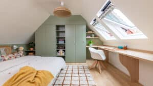 Chambre sous comble avec de grandes fenêtres de toit et un meuble sur mesure vert sauge.