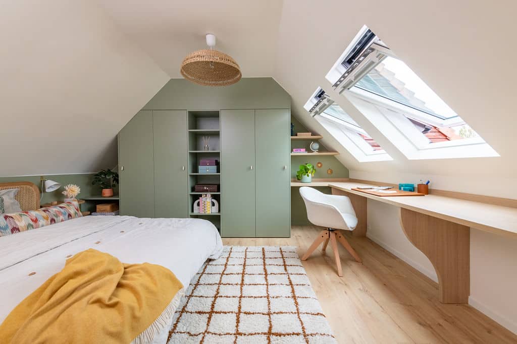 Chambre sous comble avec de grandes fenêtres de toit et un meuble sur mesure vert sauge.