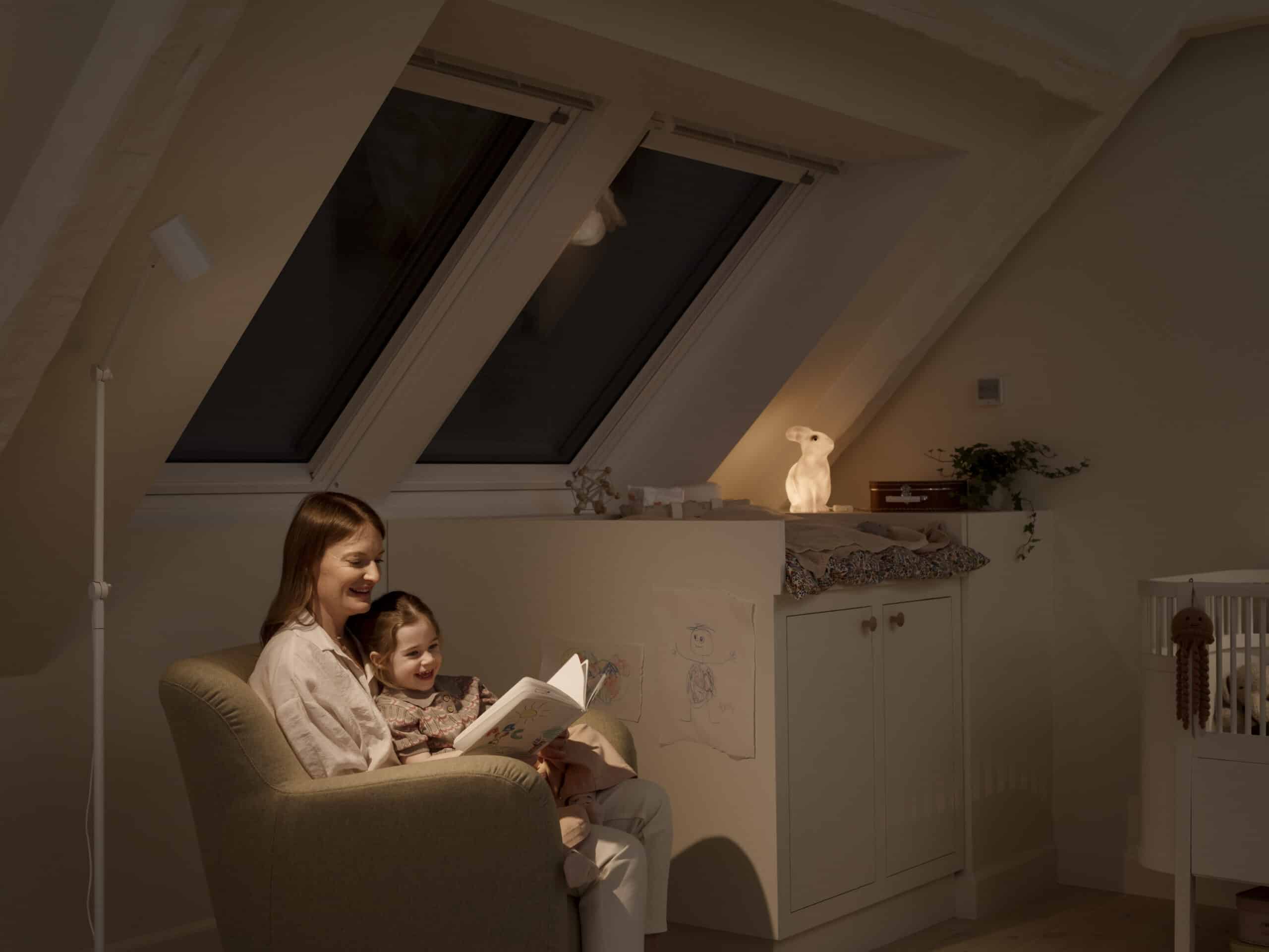 Chambre d'enfant mansardée avec plafond en pente et fenêtre de toit VELUX, coin lecture confortable.