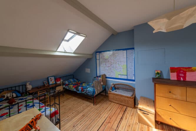 Chambre d'enfants mansardée avec plafond en pente et fenêtre de toit VELUX, décoration colorée.